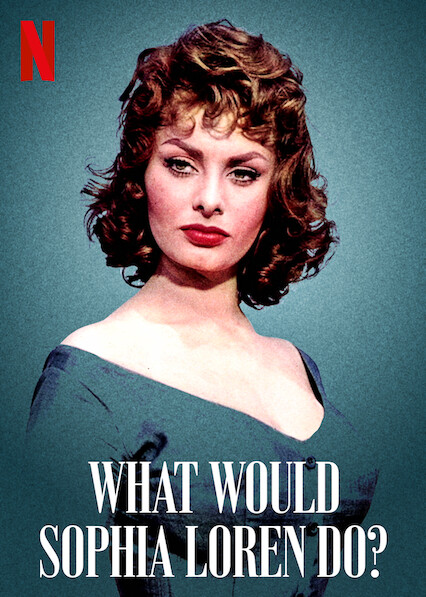 A young Sophia Loren stands in the centre of the image against a green/blue background, wearing an off the shoulder dress of the same colour. Her brown hair is short and curled as her red lipstick is the most prominent pop of colour to be seen.